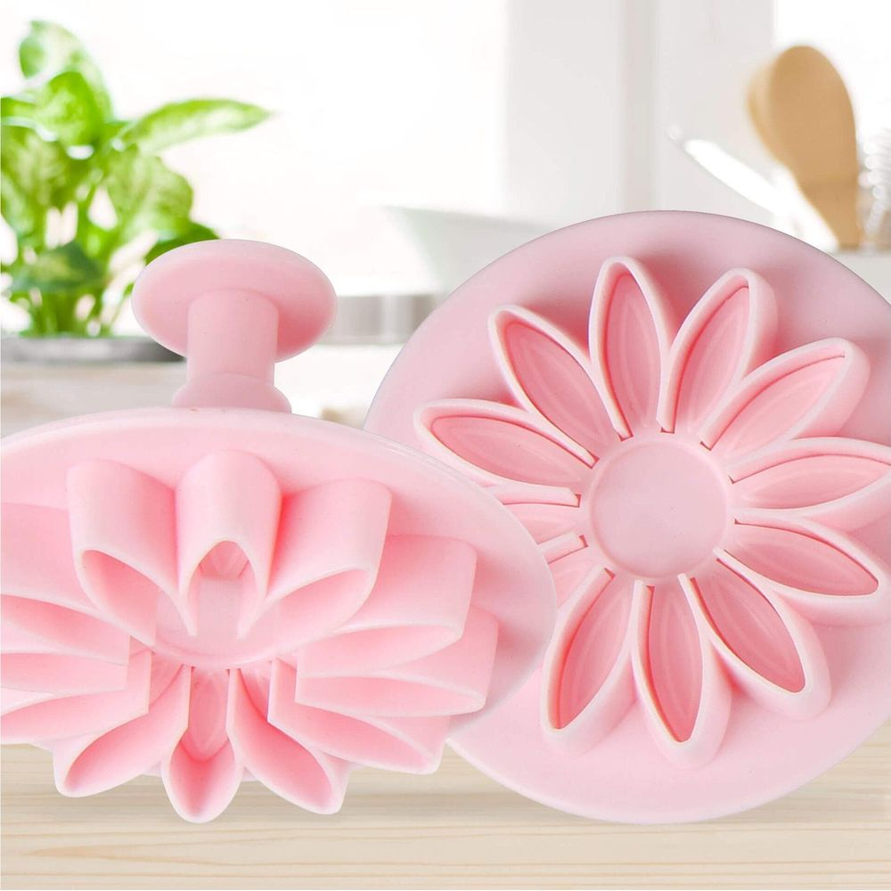 Deux emporte-pièces de fleurs roses avec détails de pétales sur une table.