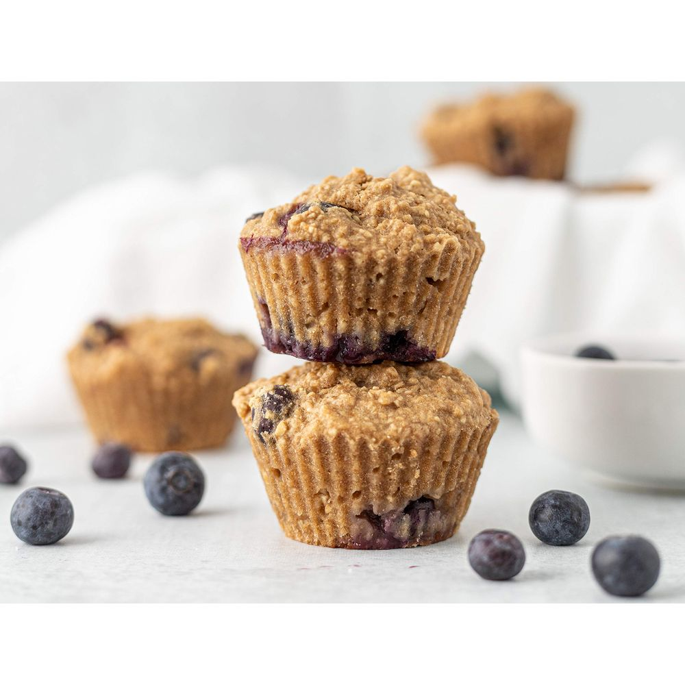 Zwei gestapelte Blaubeermuffins mit Blaubeeren auf einer hellen Oberfläche.