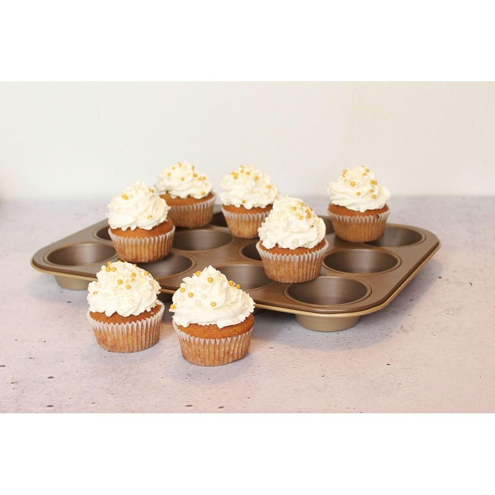 Ein Muffinblech mit acht dekorierten Cupcakes, gekrönt mit weißer Glasur und goldenen Perlen.