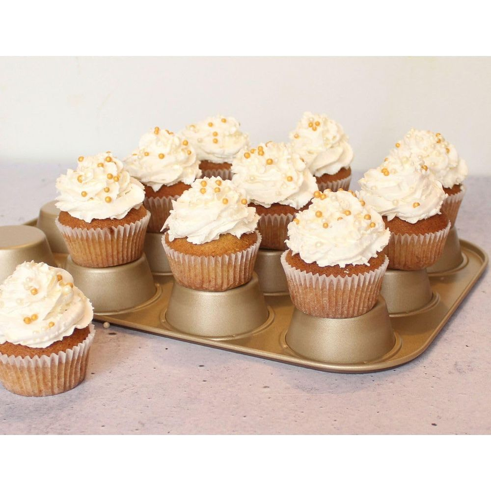 Zehn Cupcakes mit weißer Glasur und goldenen Perlen in einer goldenen Backform.