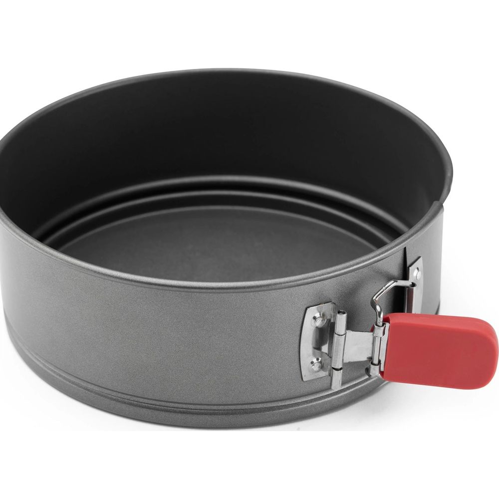 Moule à gâteau rond gris avec poignée rouge, fond blanc.