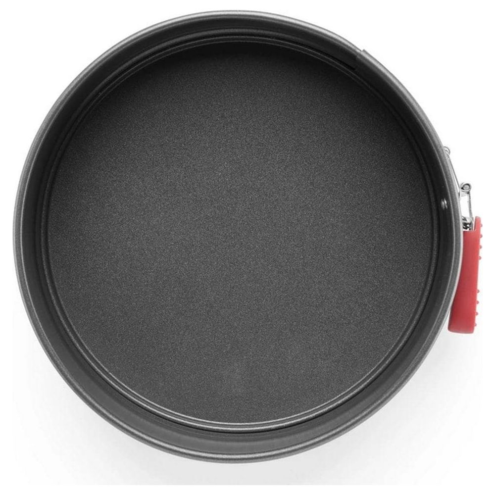 Moule à gâteau rond gris avec poignée rouge et fermoir argenté.