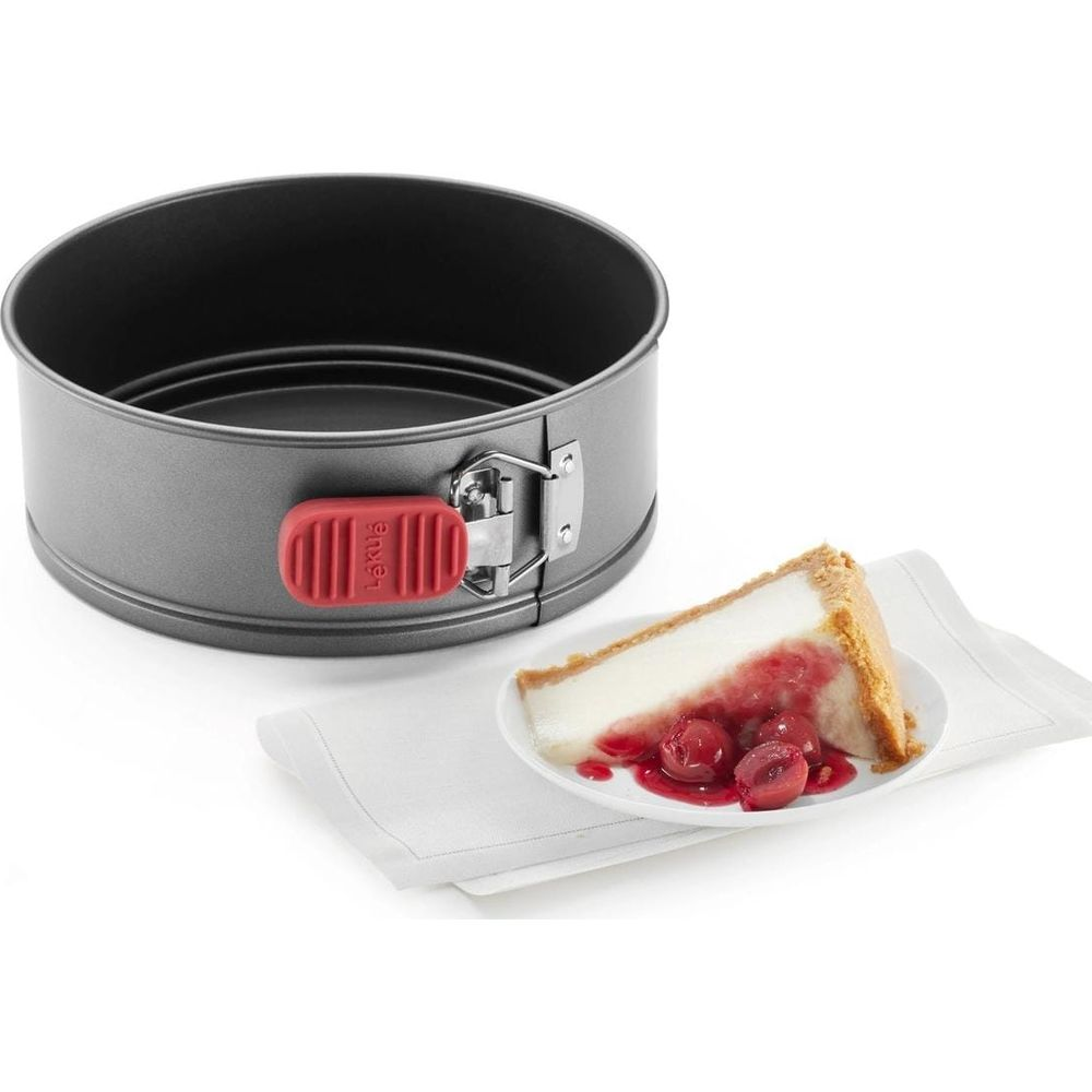 Moule à manqué gris avec poignée rouge à côté d'une part de gâteau aux cerises.