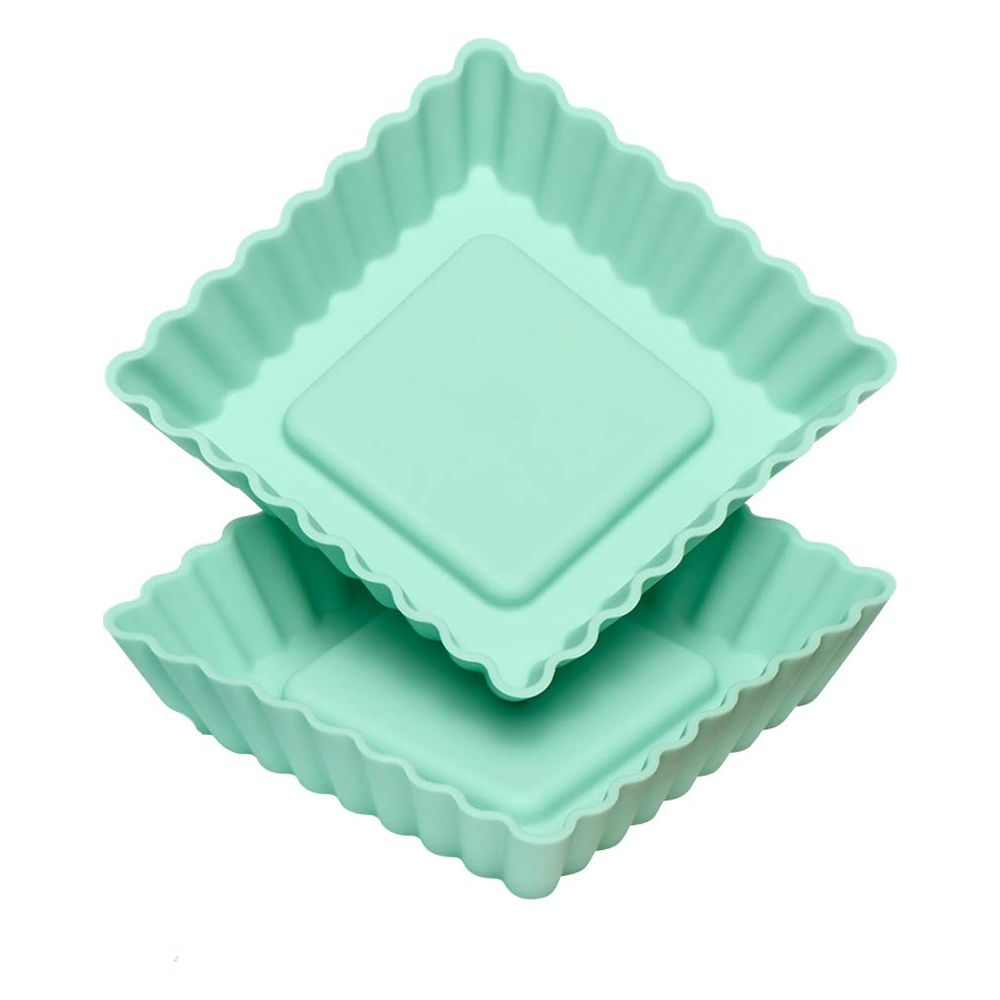 Deux moules à tarte carrés en silicone vert pastel à bords cannelés sont empilés.