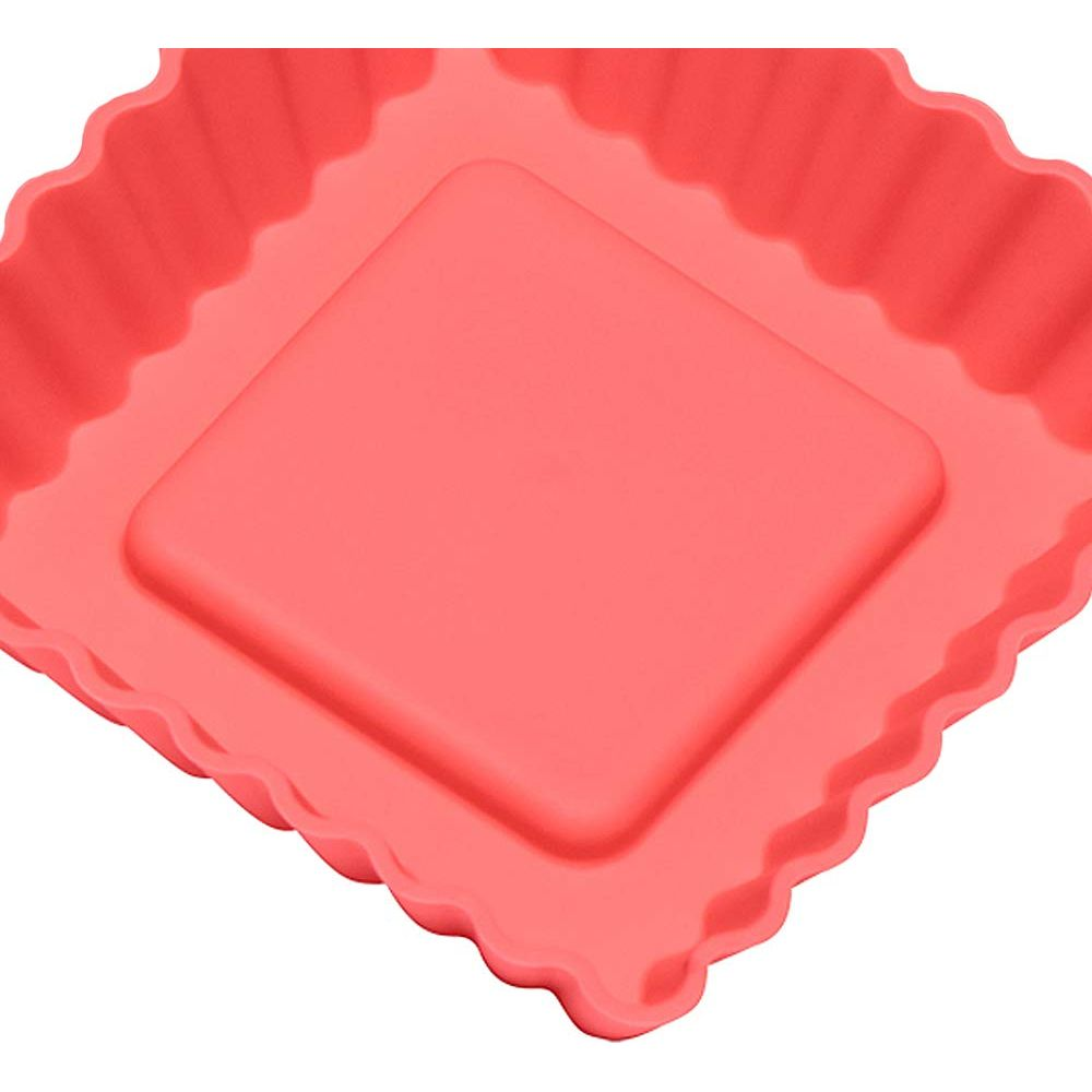 Un moule à quiche en silicone rouge à bord cannelé et base carrée.