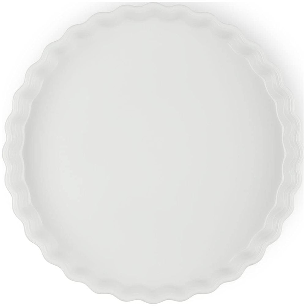 Un plat à tarte rond blanc avec un bord cannelé.