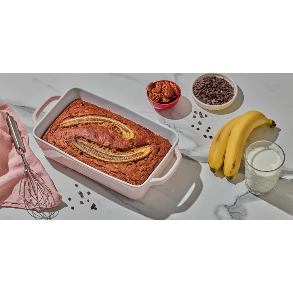 Bananenbrot in einer rosa Form mit Bananen, Nüssen, Schokostückchen und Milch.