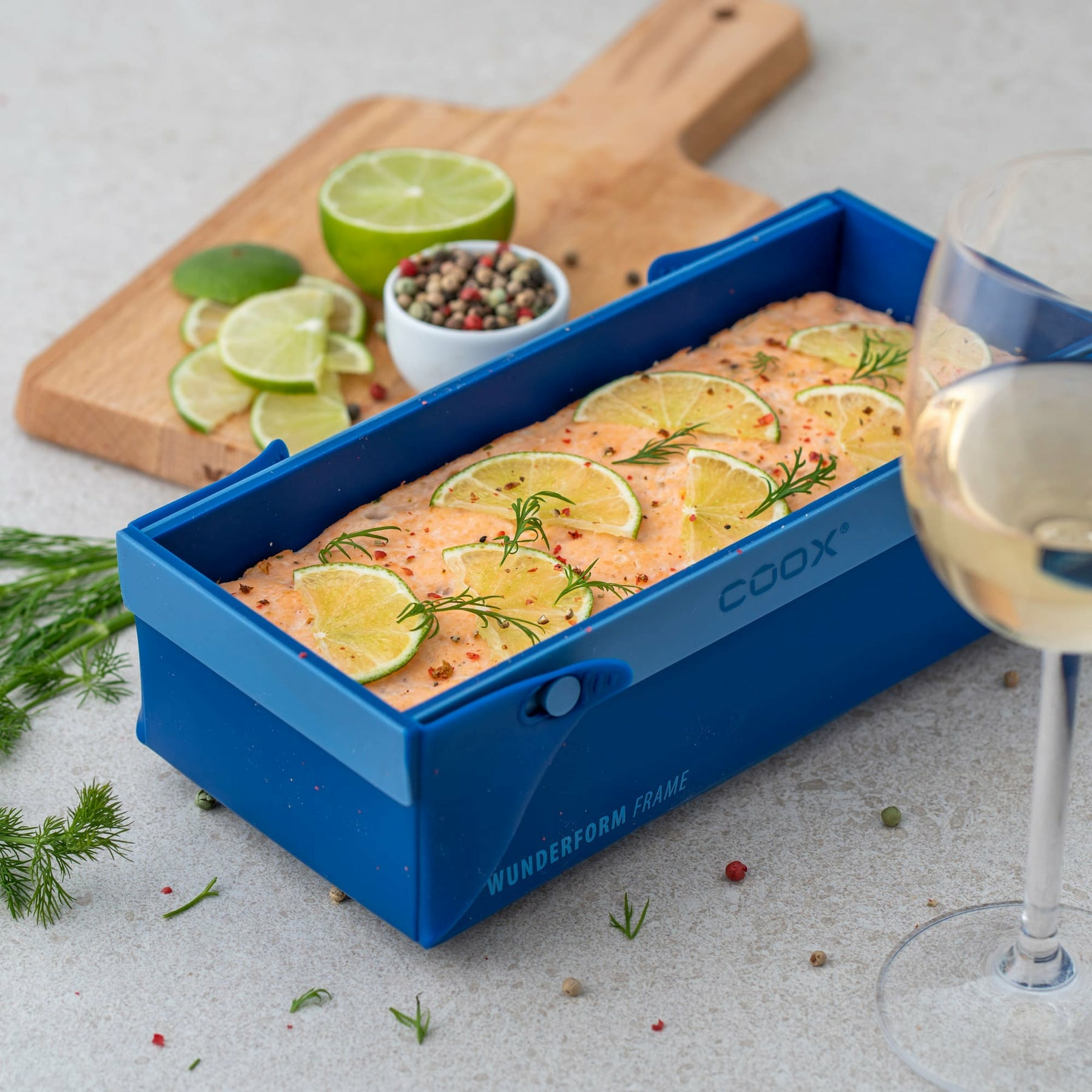 Lachs im blauen Backrahmen mit Limettenscheiben und Kräutern.