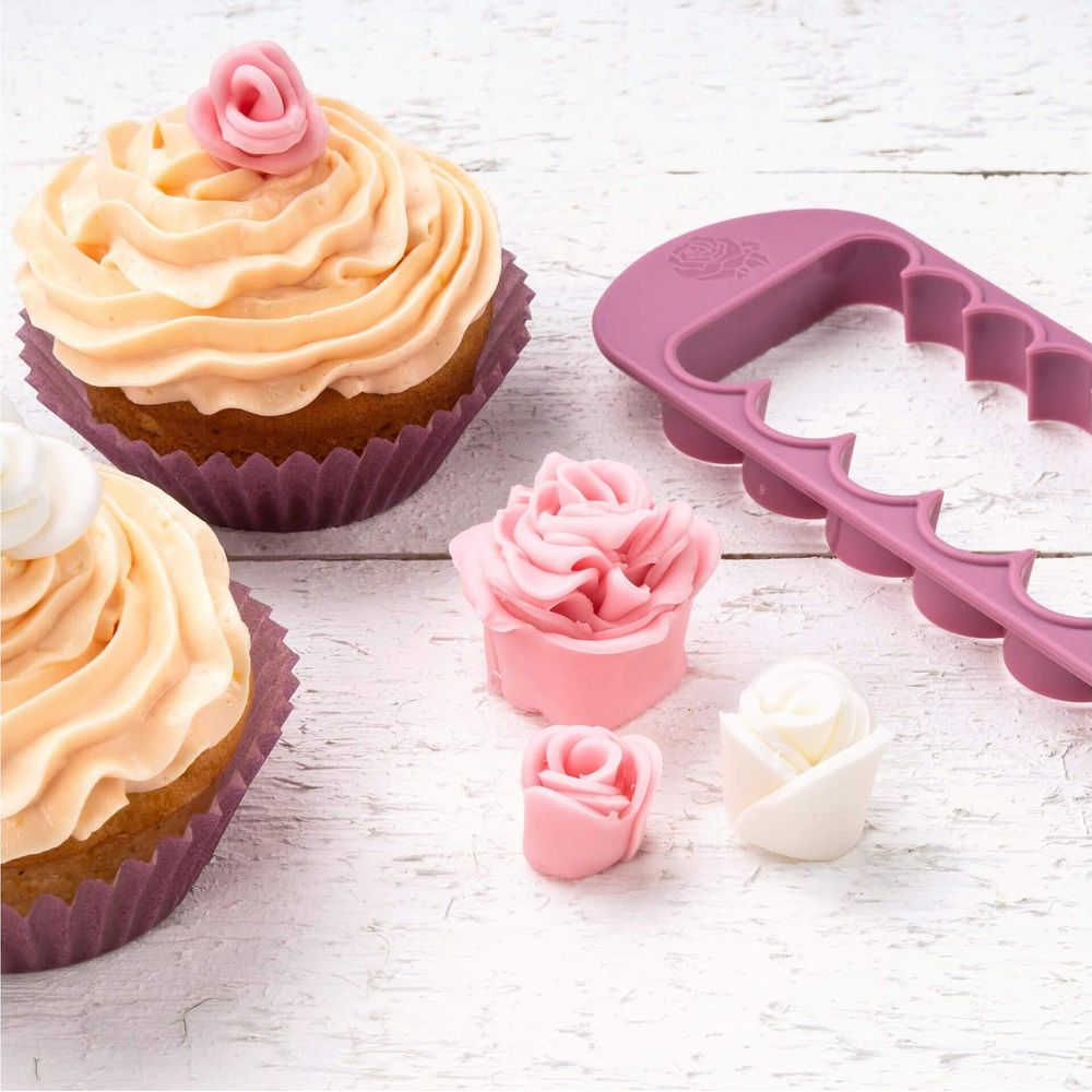 Zwei Cupcakes mit Pfirsich-Frosting und eine Rosendekoration daneben.