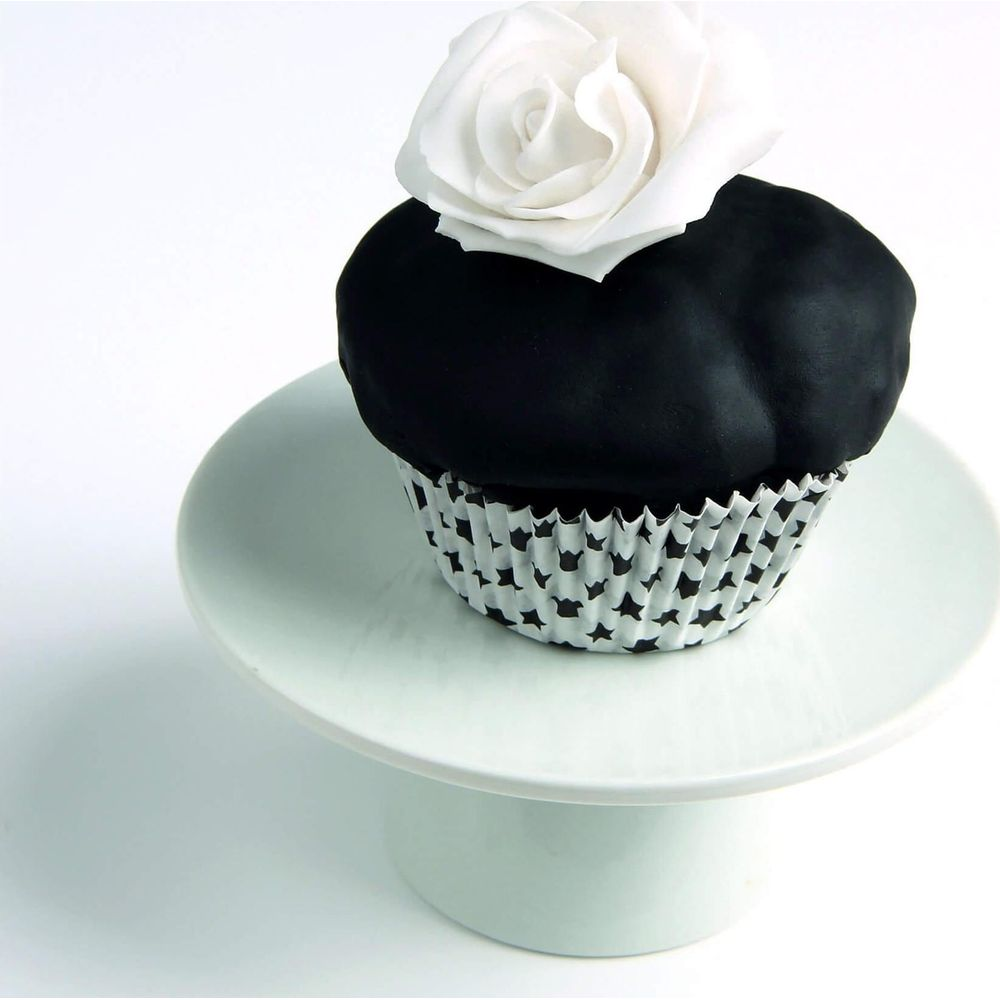 Ein schwarzer Cupcake mit Sternenpapier und einer weißen Rose darauf.