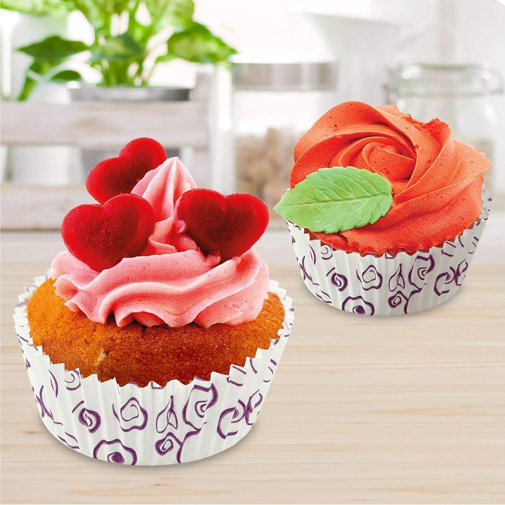 Zwei Cupcakes: einer mit rosa Zuckerguss und Herzen, einer mit rotem Rosenzuckerguss.