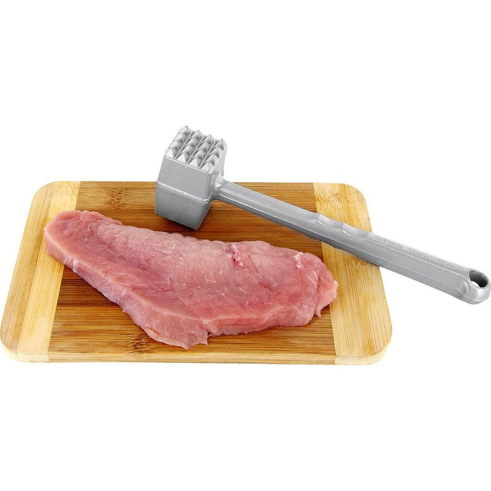 Un pezzo di carne cruda su un tagliere di legno con un batticarne accanto.