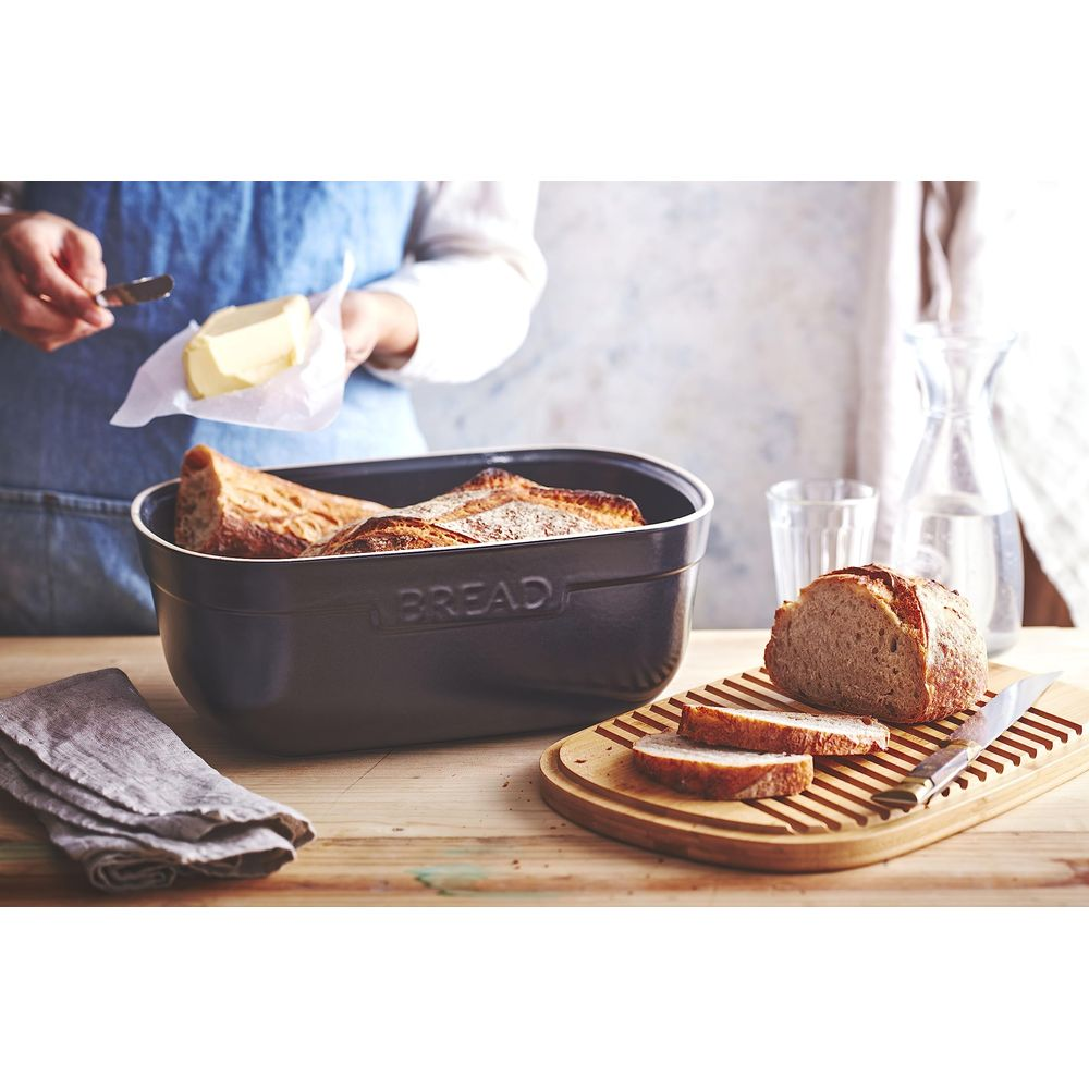Brot wird in einer schwarzen Form gebacken, daneben geschnittenes Brot und Butter.
