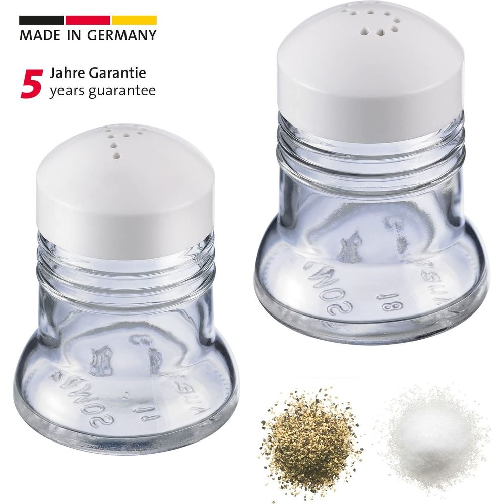 Zwei Glasstreuer mit weißen Kappen, daneben jeweils eine kleine Portion Salz und Pfeffer.