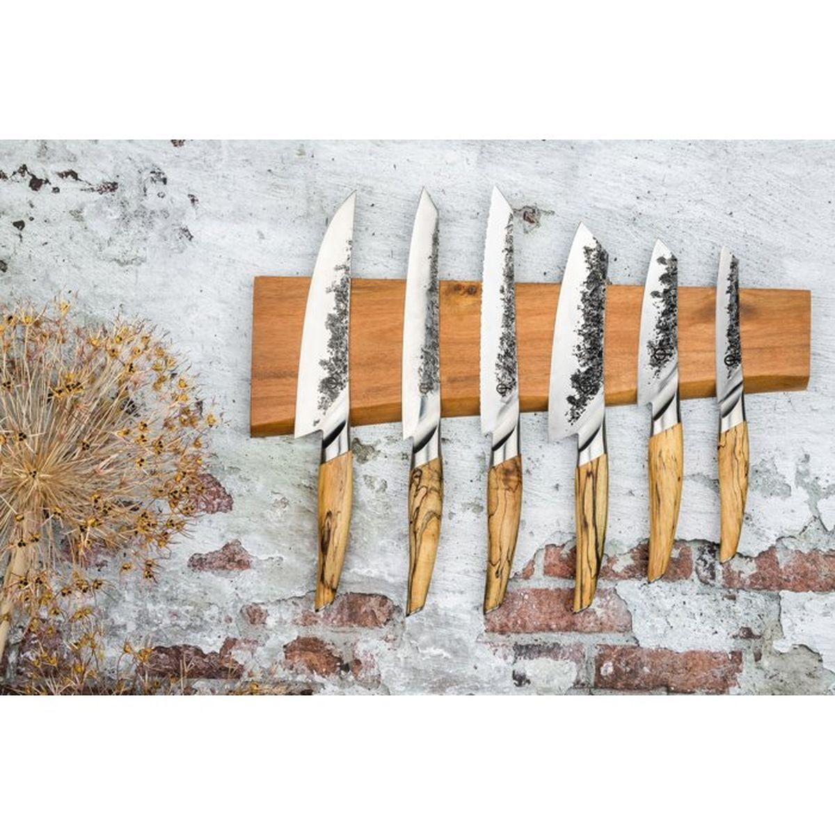 Seis cuchillos con mangos de madera en un bloque de madera en una pared.
