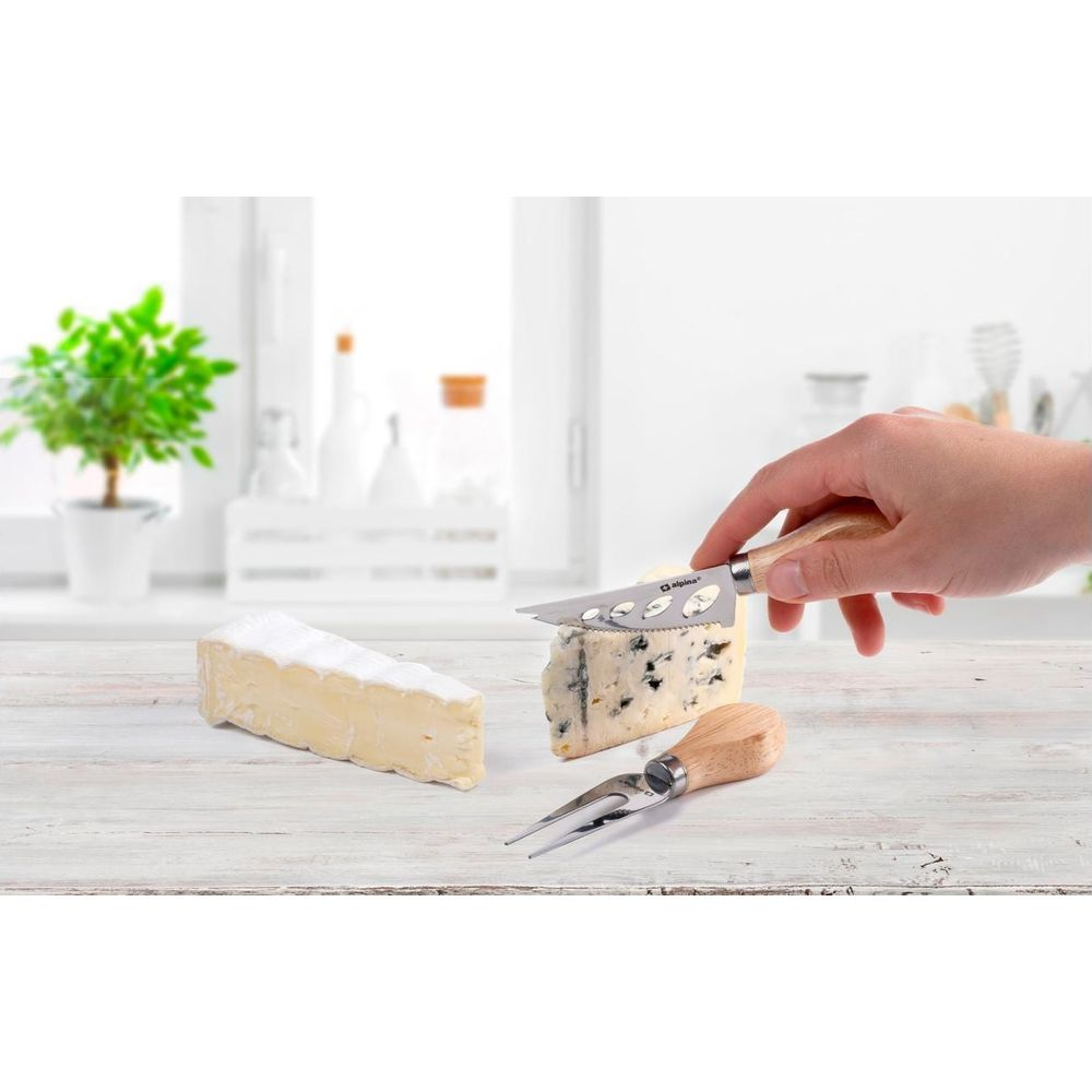 Ein Mann schneidet Blauschimmelkäse mit einem Käsemesser. Daneben liegt ein Stück Brie.