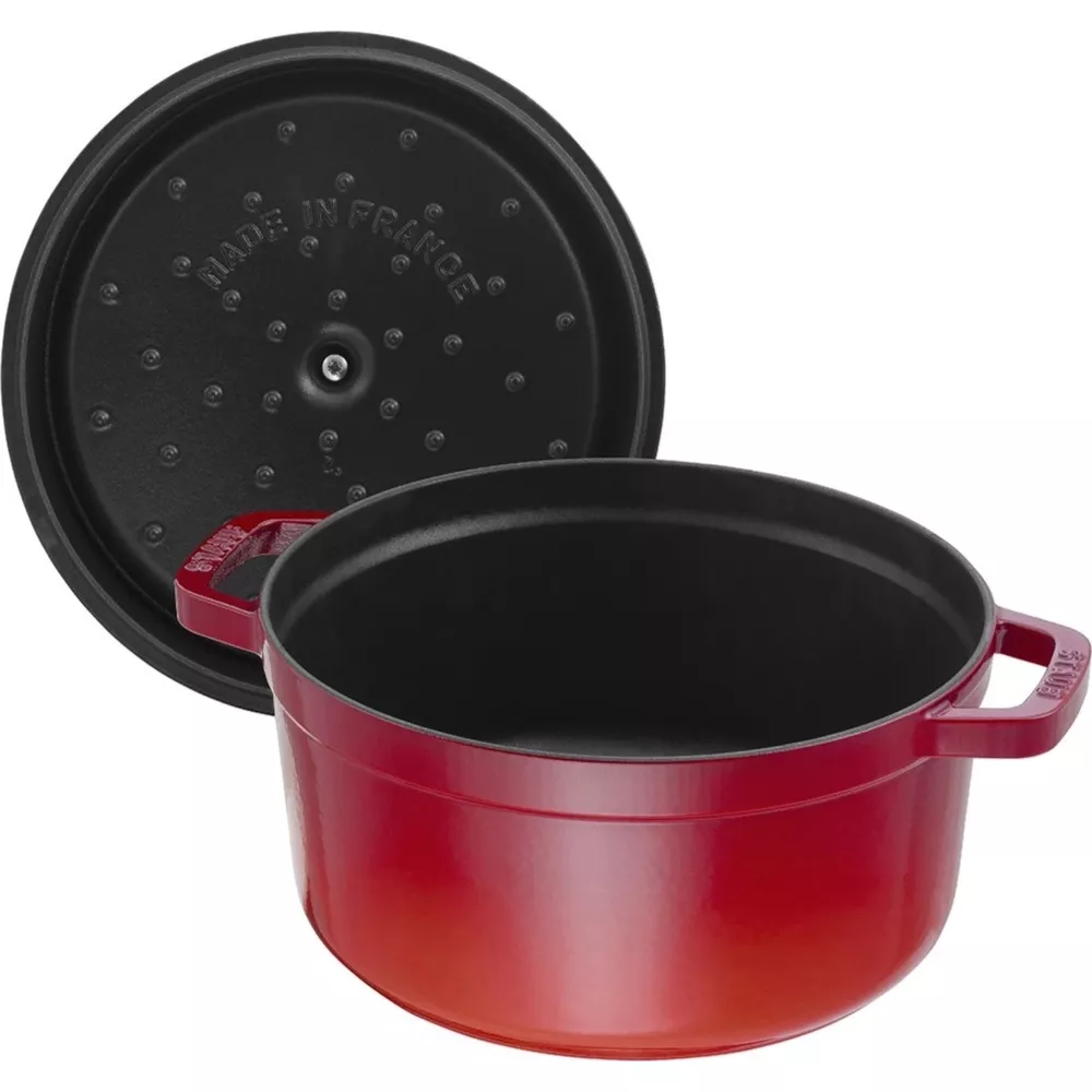 Une cocotte en fonte émaillée rouge avec son couvercle noir à côté.