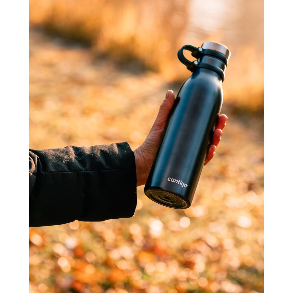 Eine Hand hält eine schwarze Contigo-Wasserflasche im Freien mit verschwommenem Herbstlaub.