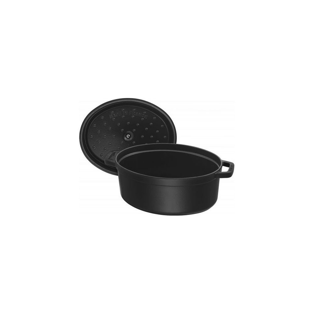 Une cocotte ovale en fonte noire avec son couvercle posé à côté.