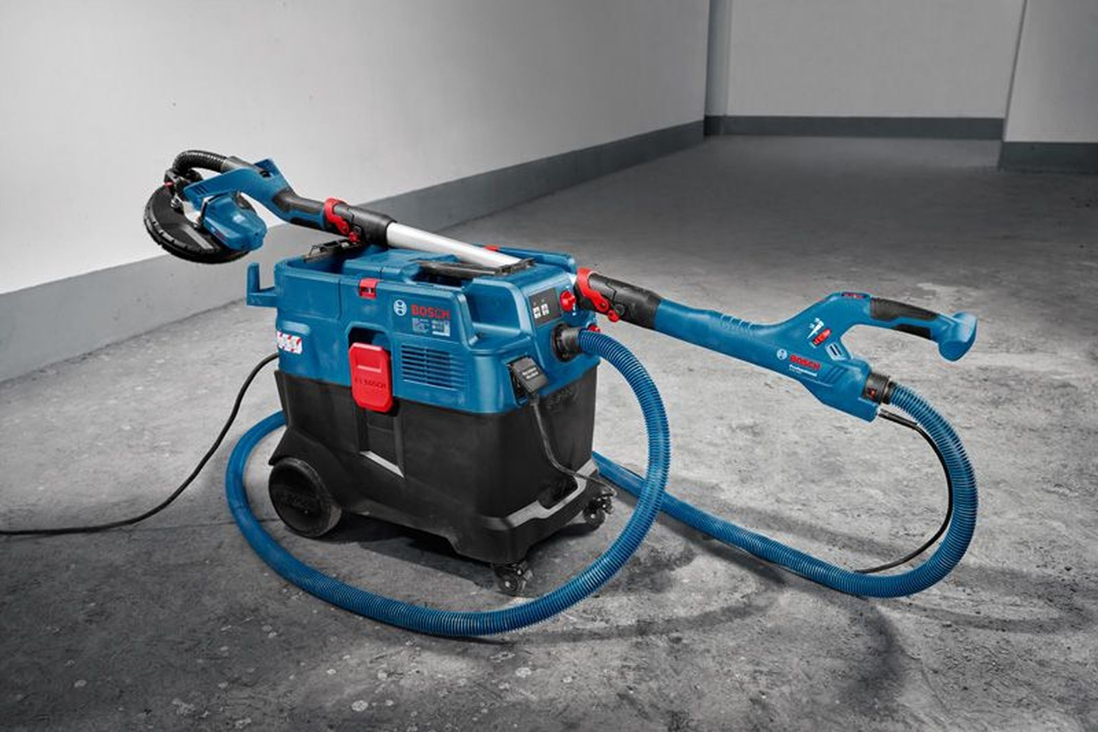 Blauer Bosch-Sauger mit Schrubber und Schlauch auf Betonboden.