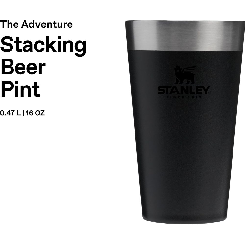 Vaso de cerveza Stanley negro con borde plateado y logo. Texto: The Adventure Stacking Beer Pint.