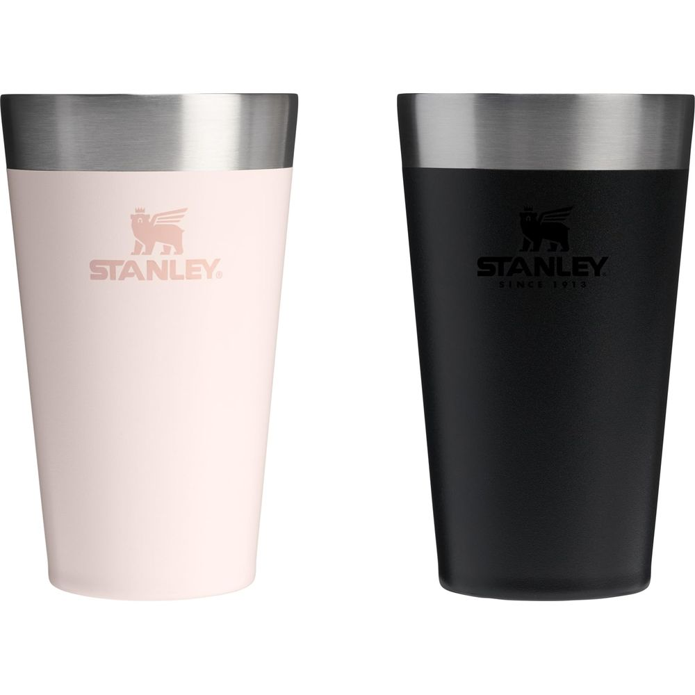Dos tazas Stanley: una rosa pálido, una negra, con bordes plateados.