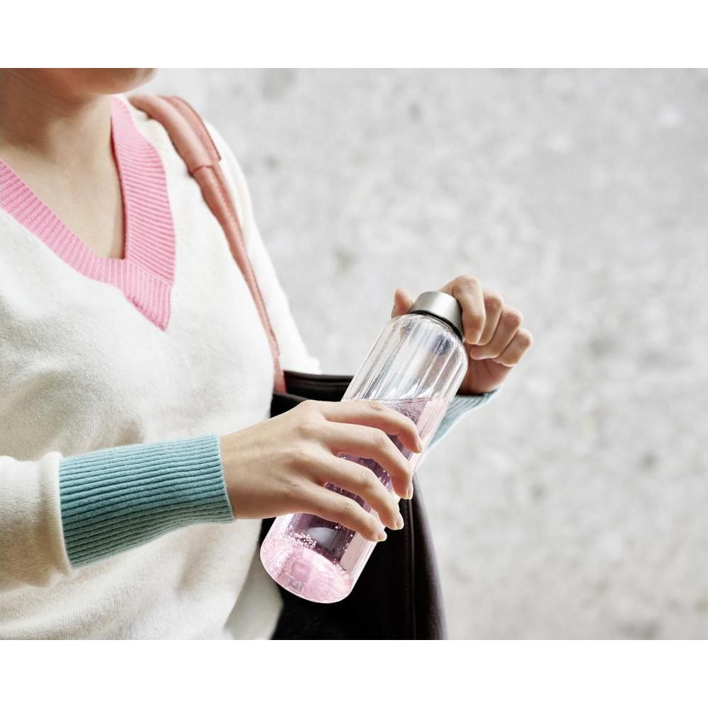Eine Frau hält eine durchsichtige Flasche mit rosa Flüssigkeit.