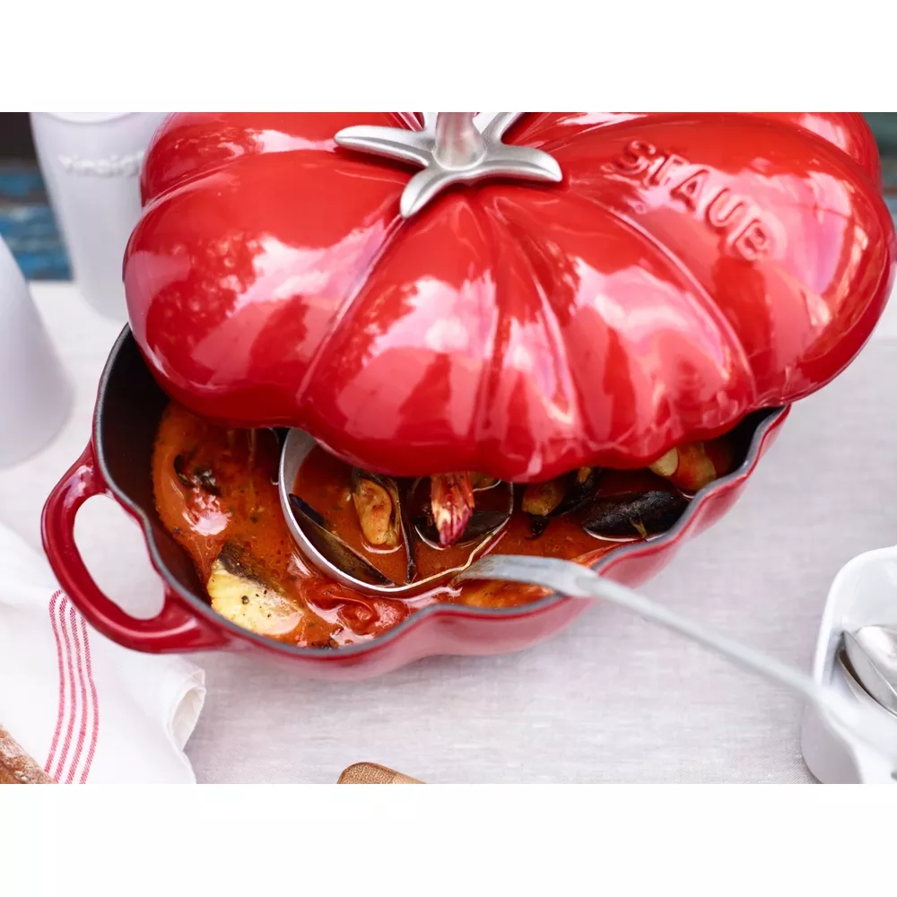 Marmite rouge en forme de citrouille avec moules en sauce, louche à côté.