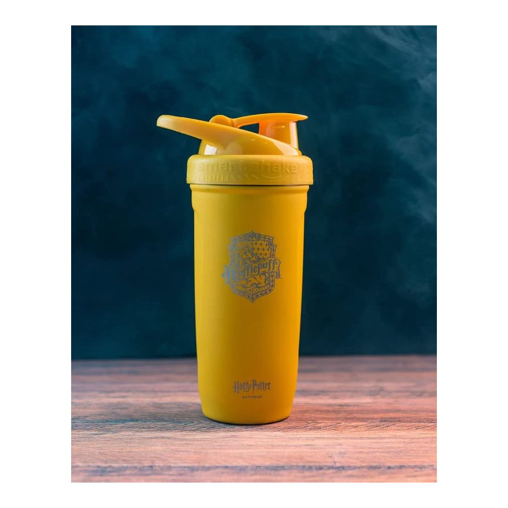 Gelber Harry Potter Hufflepuff Becher mit Aufdruck auf Holztisch.