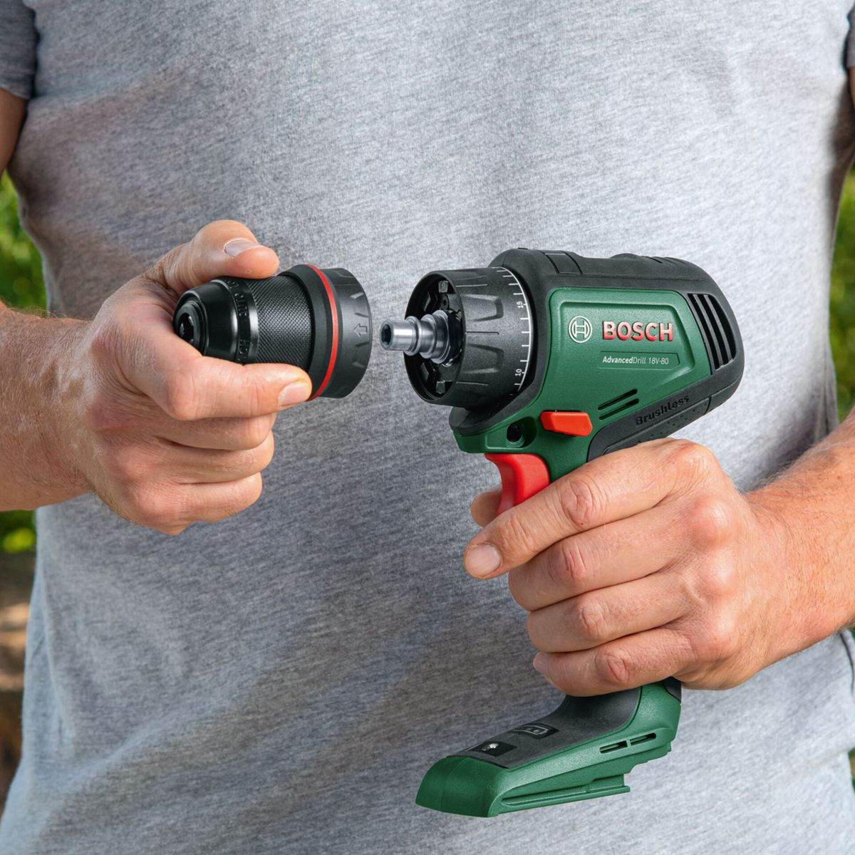 Mani che attaccano una punta da trapano a un trapano Bosch verde con accenti rossi.