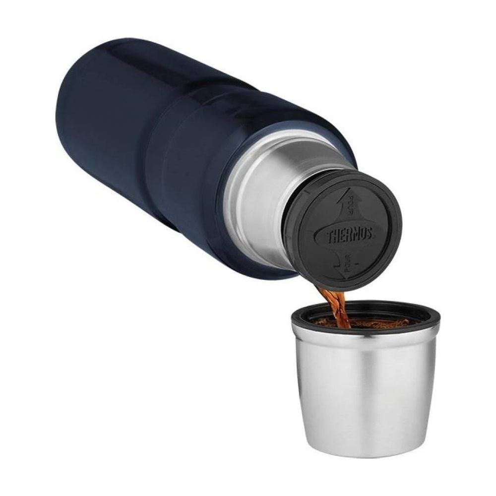 Dunkelblauer Thermosbehälter gießt Kaffee in einen silbernen Becher.