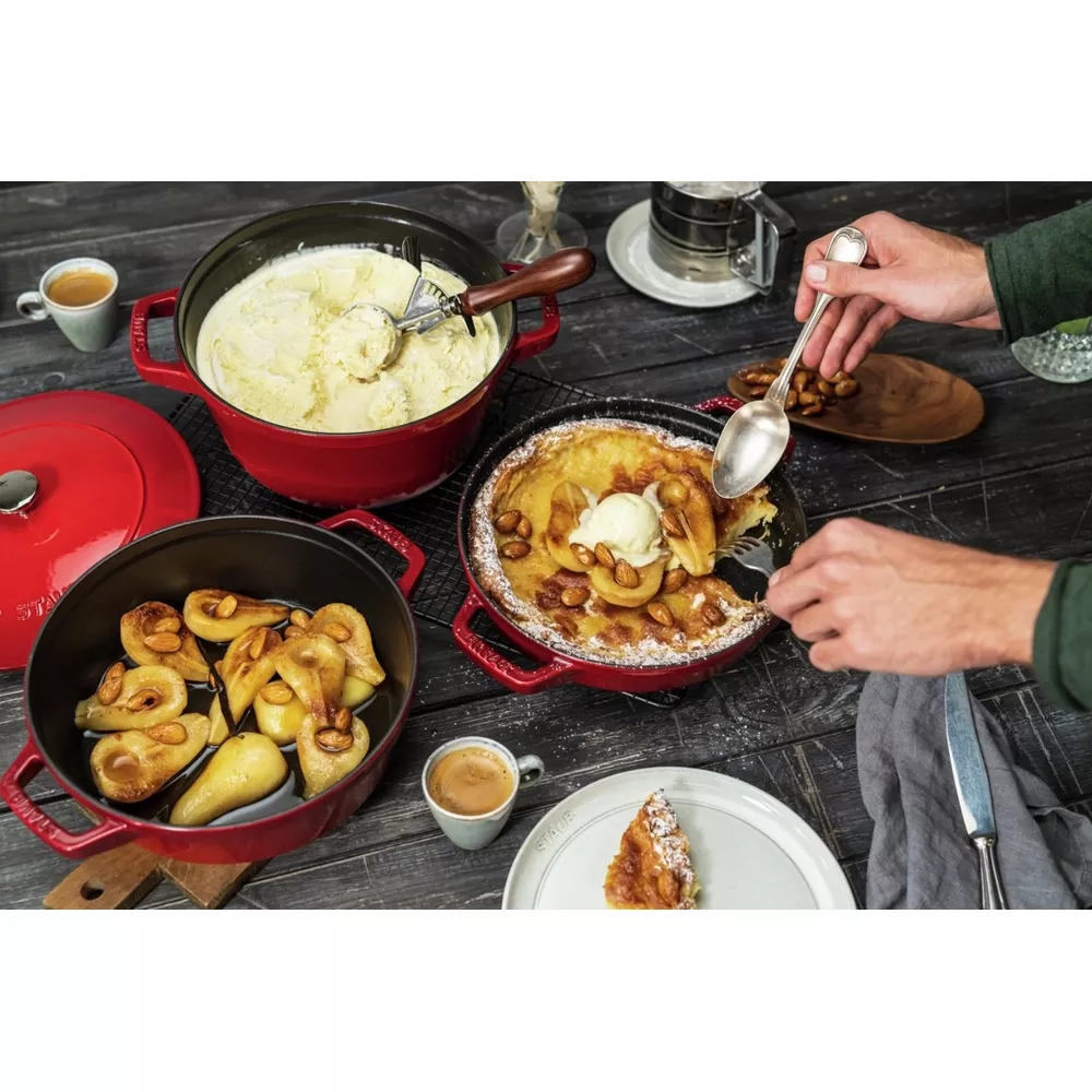 Une table avec des desserts : glace, poires cuites et crêpe Dutch Baby.