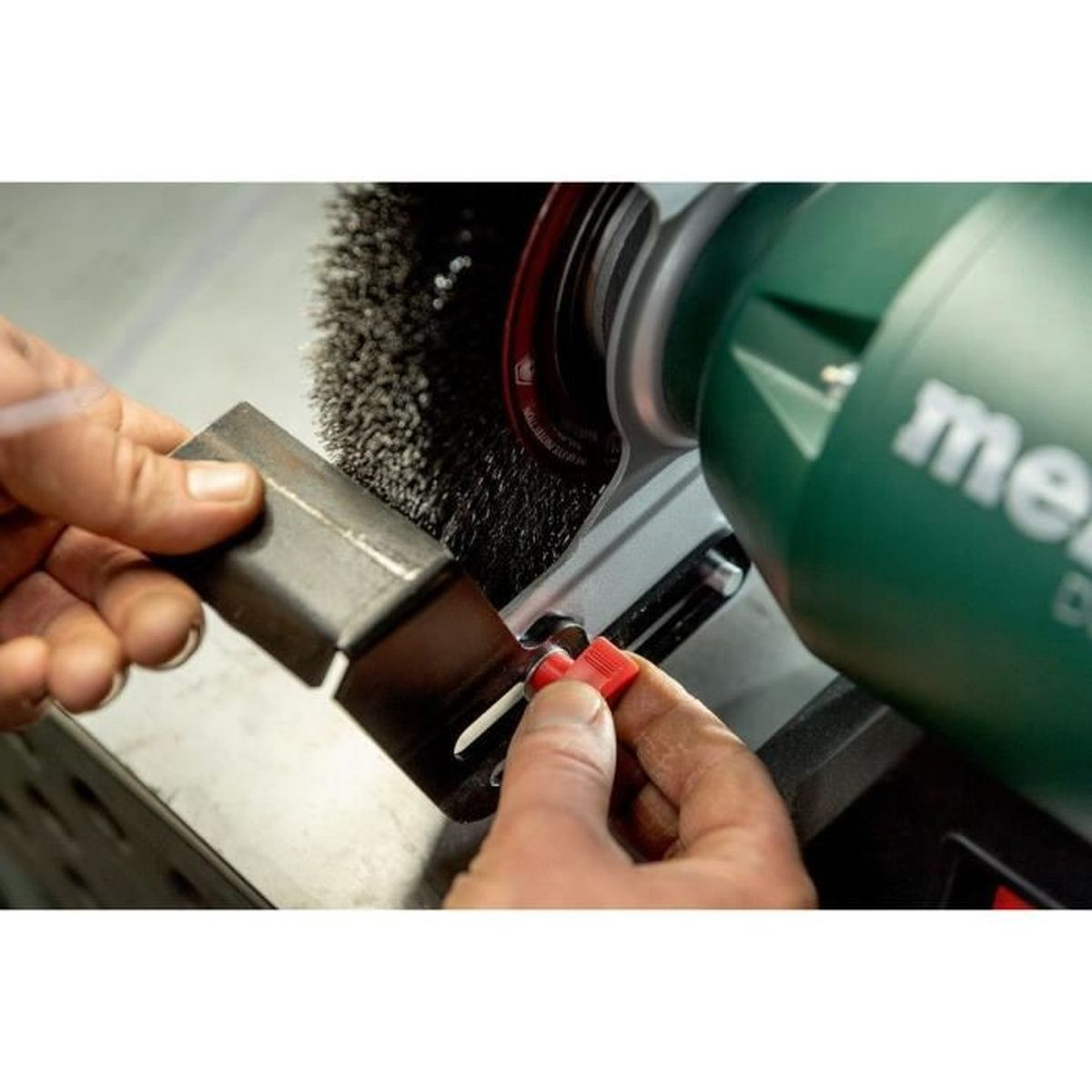 Une personne utilise une meule et une brosse métallique pour nettoyer du métal.
