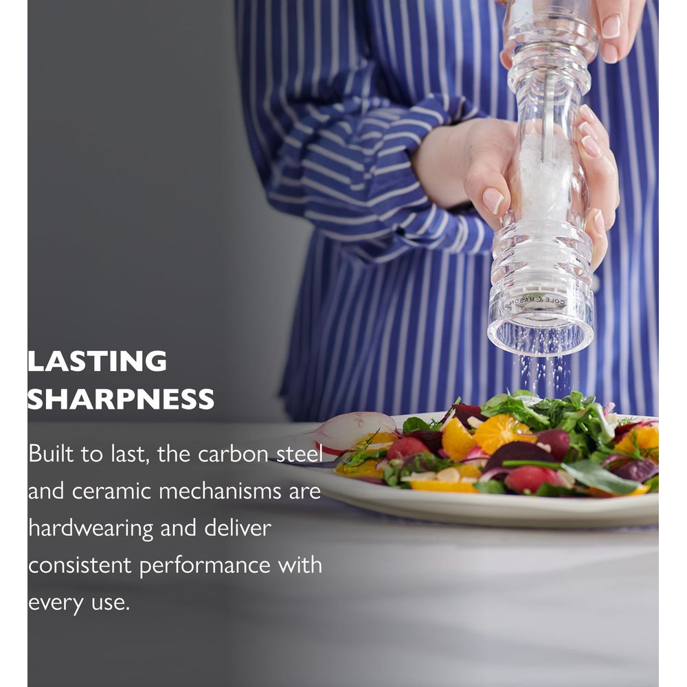 Eine Person würzt einen Salat mit einer Glasmühle.