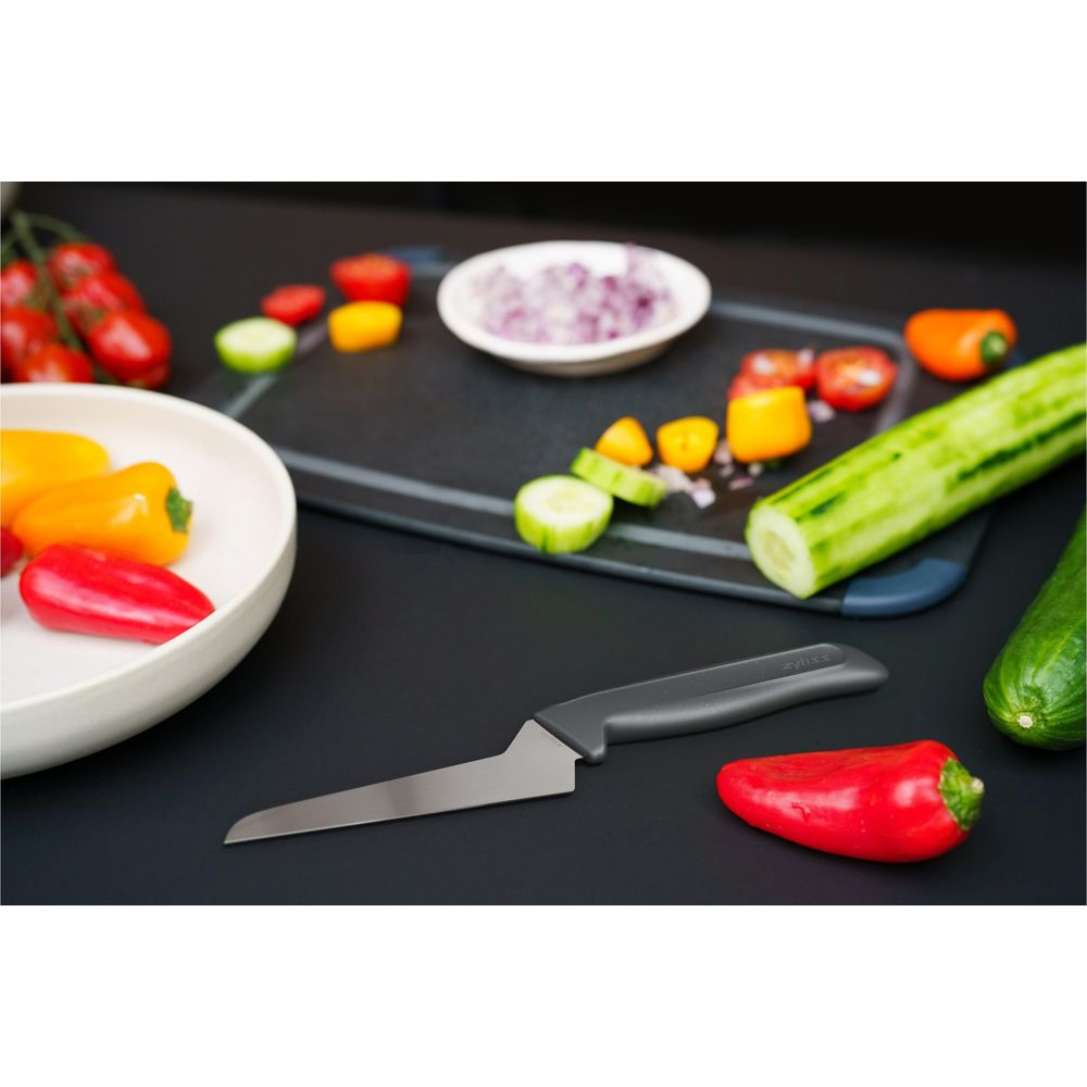 Ein Messer liegt neben geschnittenen Paprika, Gurken, Tomaten und Zwiebeln.
