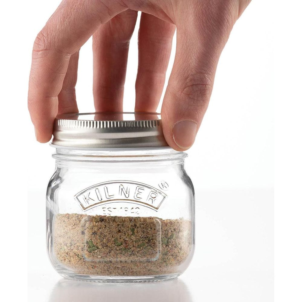 Eine Hand schließt einen kleinen Kilner-Glasbehälter mit Gewürzen.