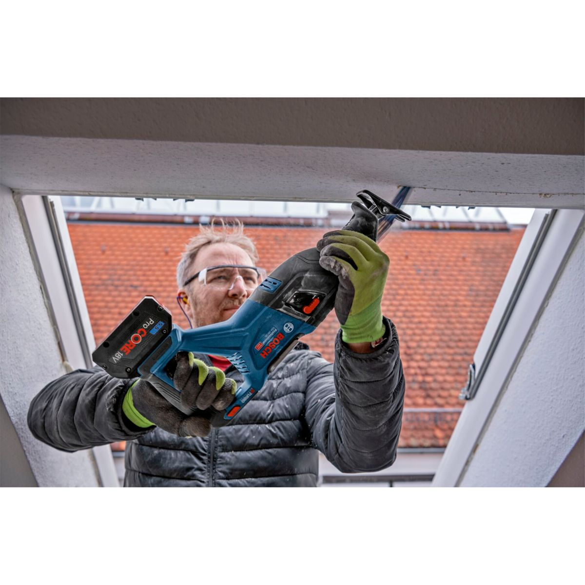 Mann mit Schutzbrille und Handschuhen benutzt Säge an Decke.