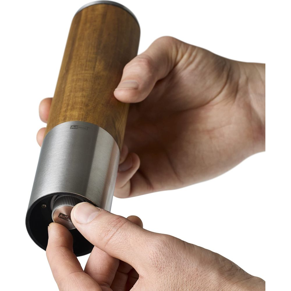 Person stellt Mühlen-Mahlgrad ein: Holzgehäuse, Metallbasis, Einstellknopf.