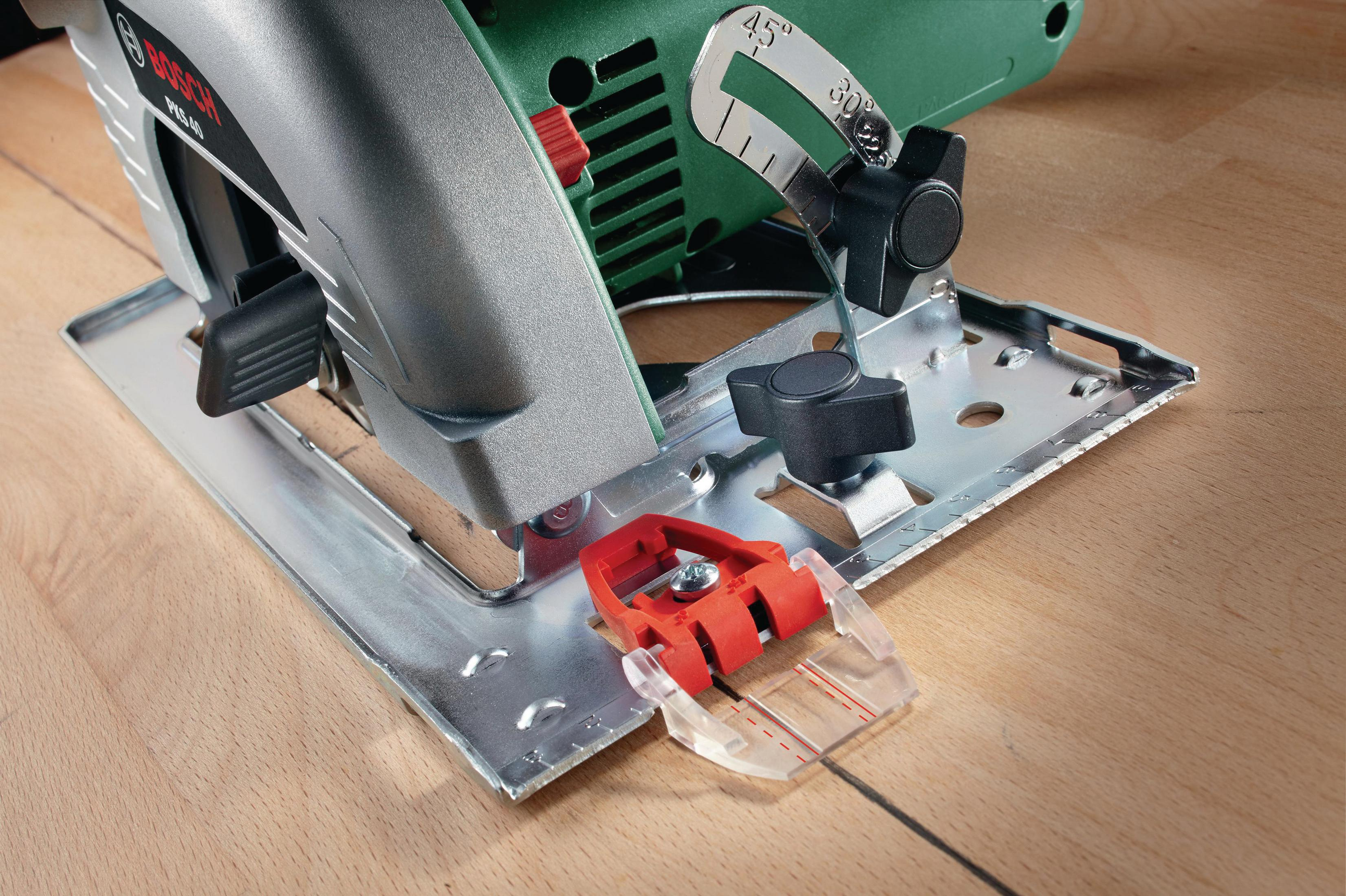 Gros plan d'une scie circulaire Bosch avec sabot guide rouge sur bois.