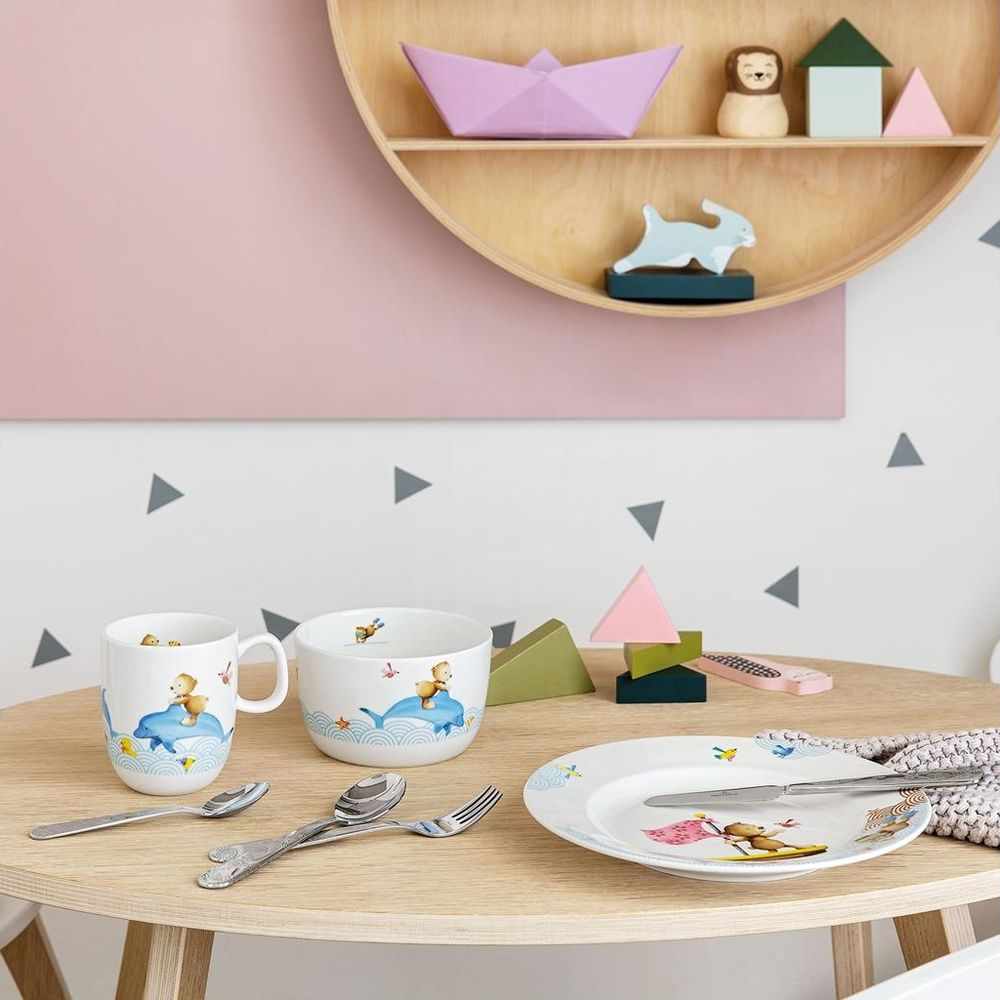 Ein Kindertischgedeck mit Becher, Schüssel, Teller und Besteck, verziert mit Meeresbewohnern.