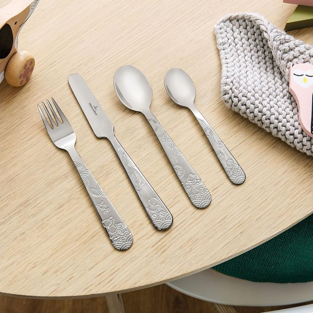 Vier Edelstahlbesteckteile mit geprägten Tiermotiven auf einem Holztisch.