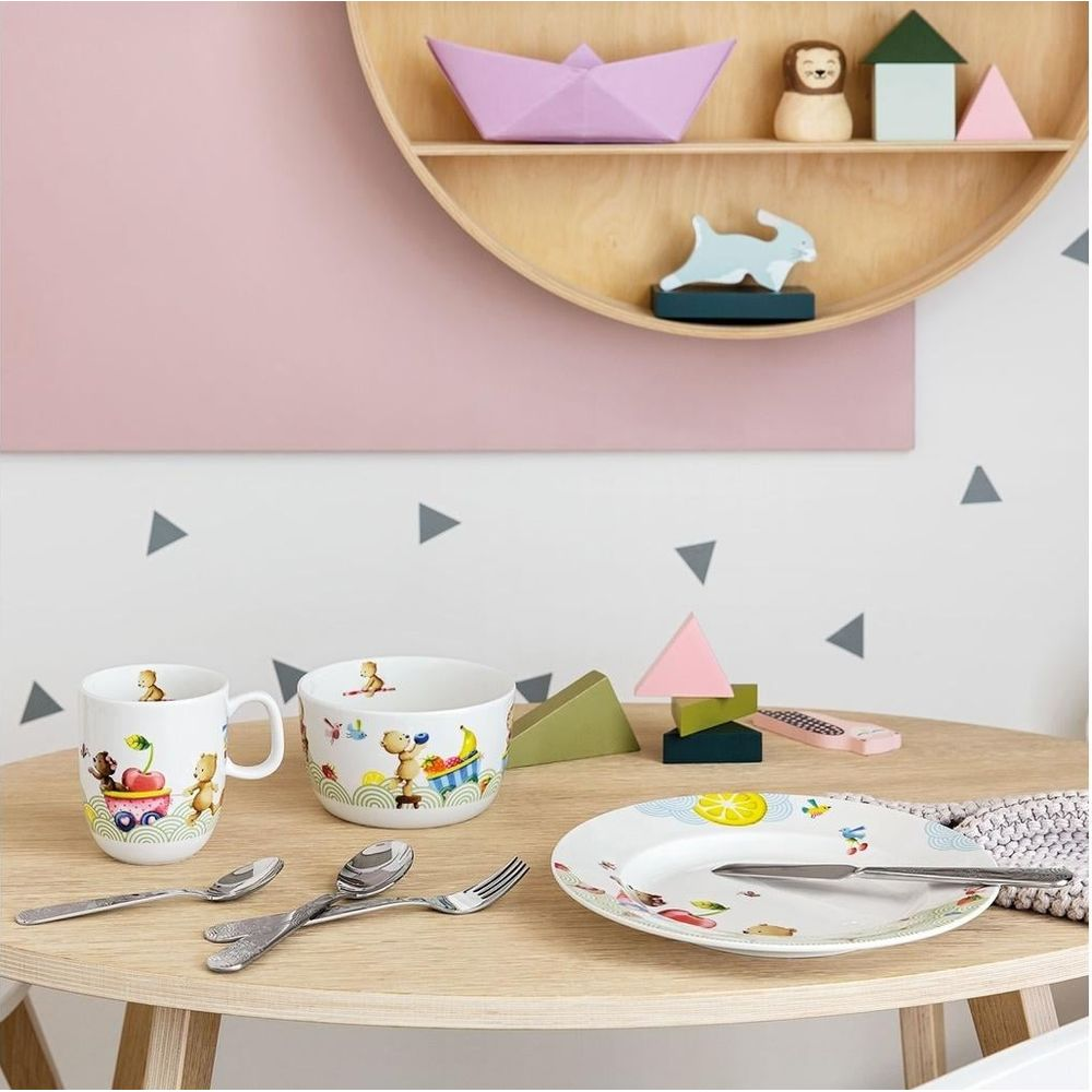 Kindergeschirr mit Bärenmotiv auf einem Holztisch. Beinhaltet Tasse, Schüssel, Teller, Besteck.