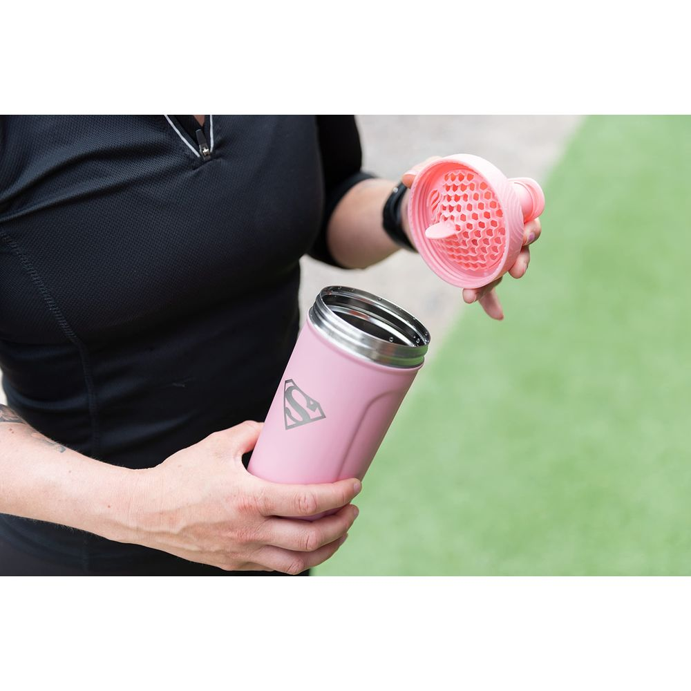 Eine Person hält einen rosa Trinkbecher mit Superman-Logo und den offenen Deckel.