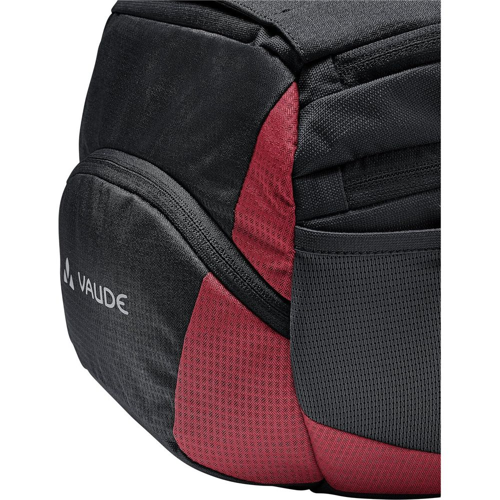 Gros plan d'un sac à dos avec des sections en tissu noir et rouge et le logo Vaude.