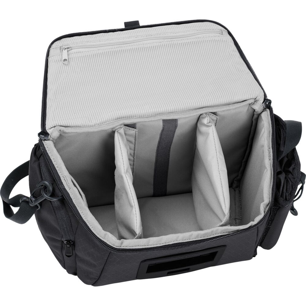 Sac photo noir ouvert avec séparateurs rembourrés et poche intérieure en filet. Fond blanc.