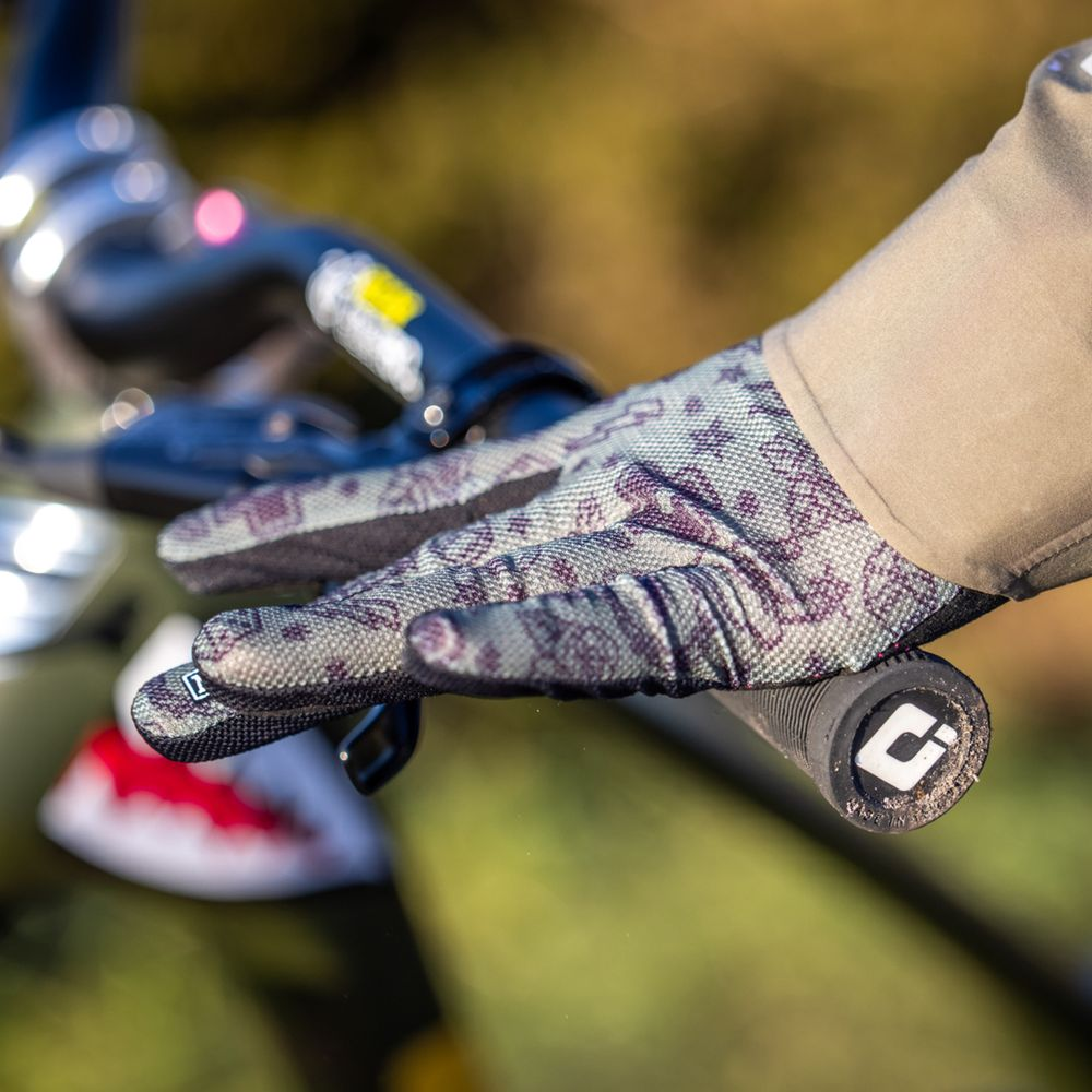 Main gantée à motif saisit un guidon de vélo avec une poignée.