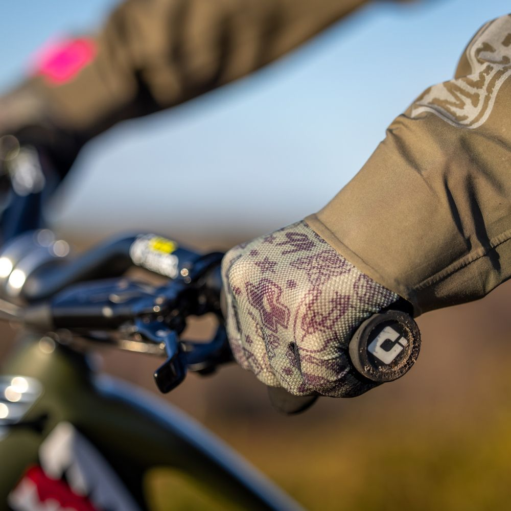 Gros plan de mains gantées tenant le guidon d'un vélo.