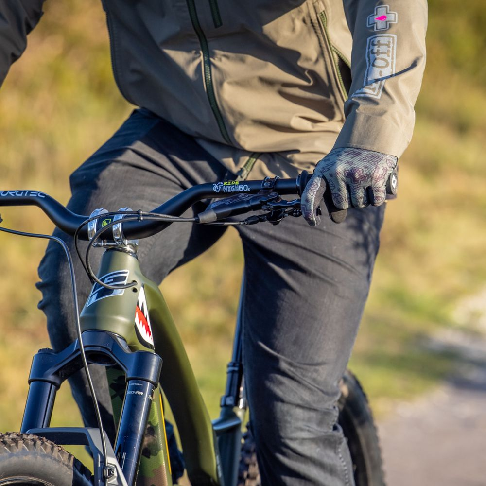 Une personne en veste verte et pantalon sombre roule sur un VTT.