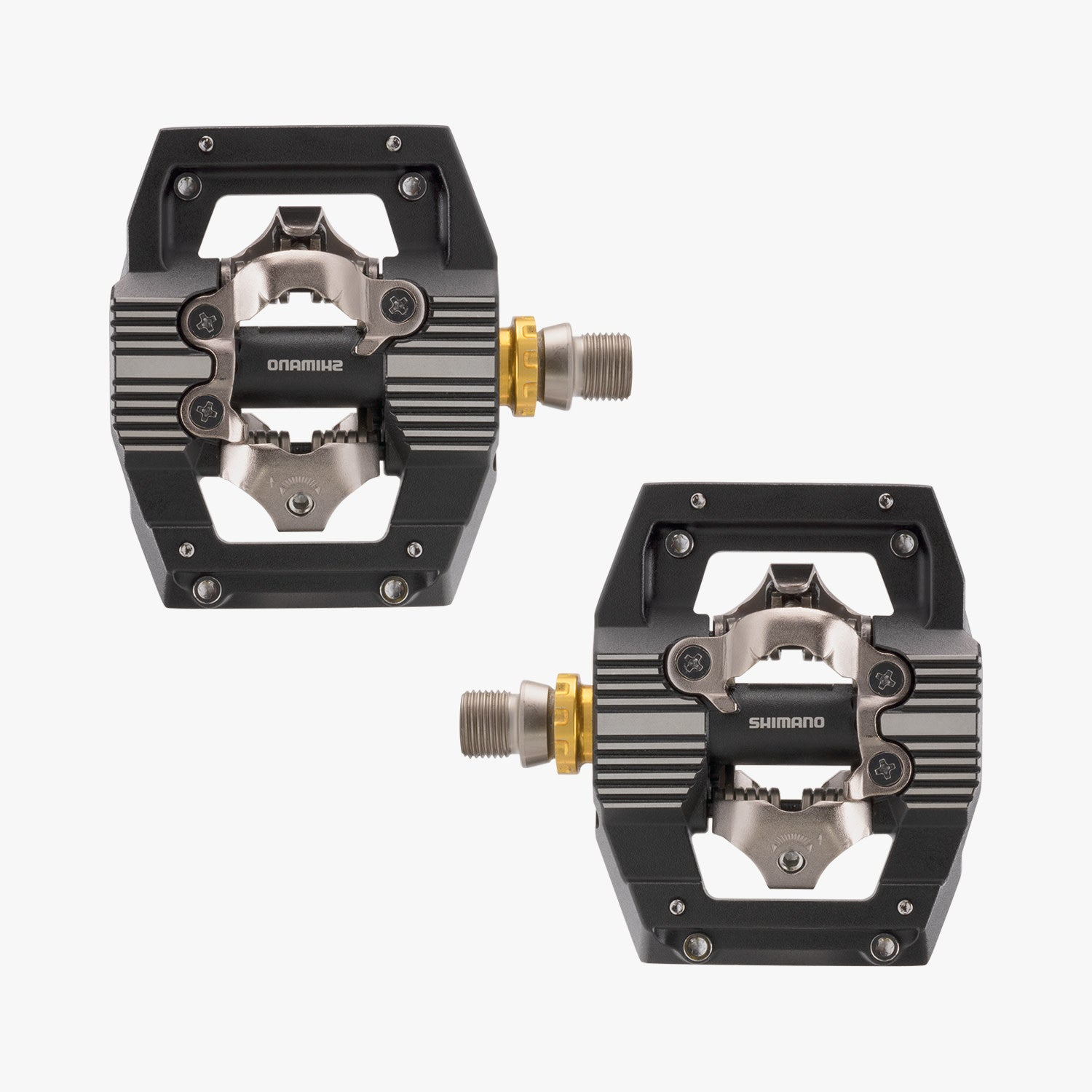 Zwei schwarze Shimano Fahrradpedale mit silbernen Akzenten und goldenen Spindeln, weißer Hintergrund.