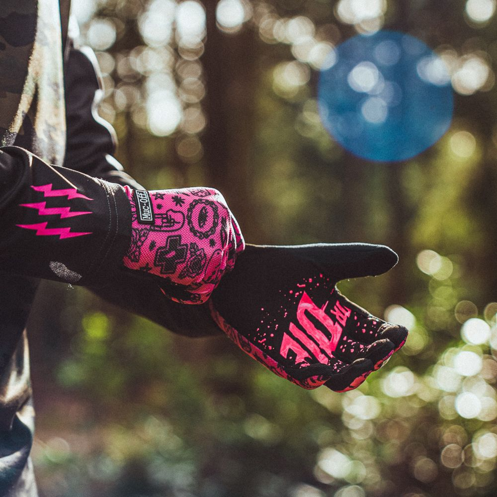 Person trägt schwarze Handschuhe mit pinken Grafiken und Blitzen, im Freien.